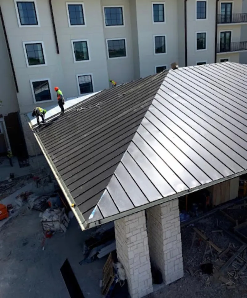 Crew installing standing seam metal roof panels on a commercial project in Orange Cove